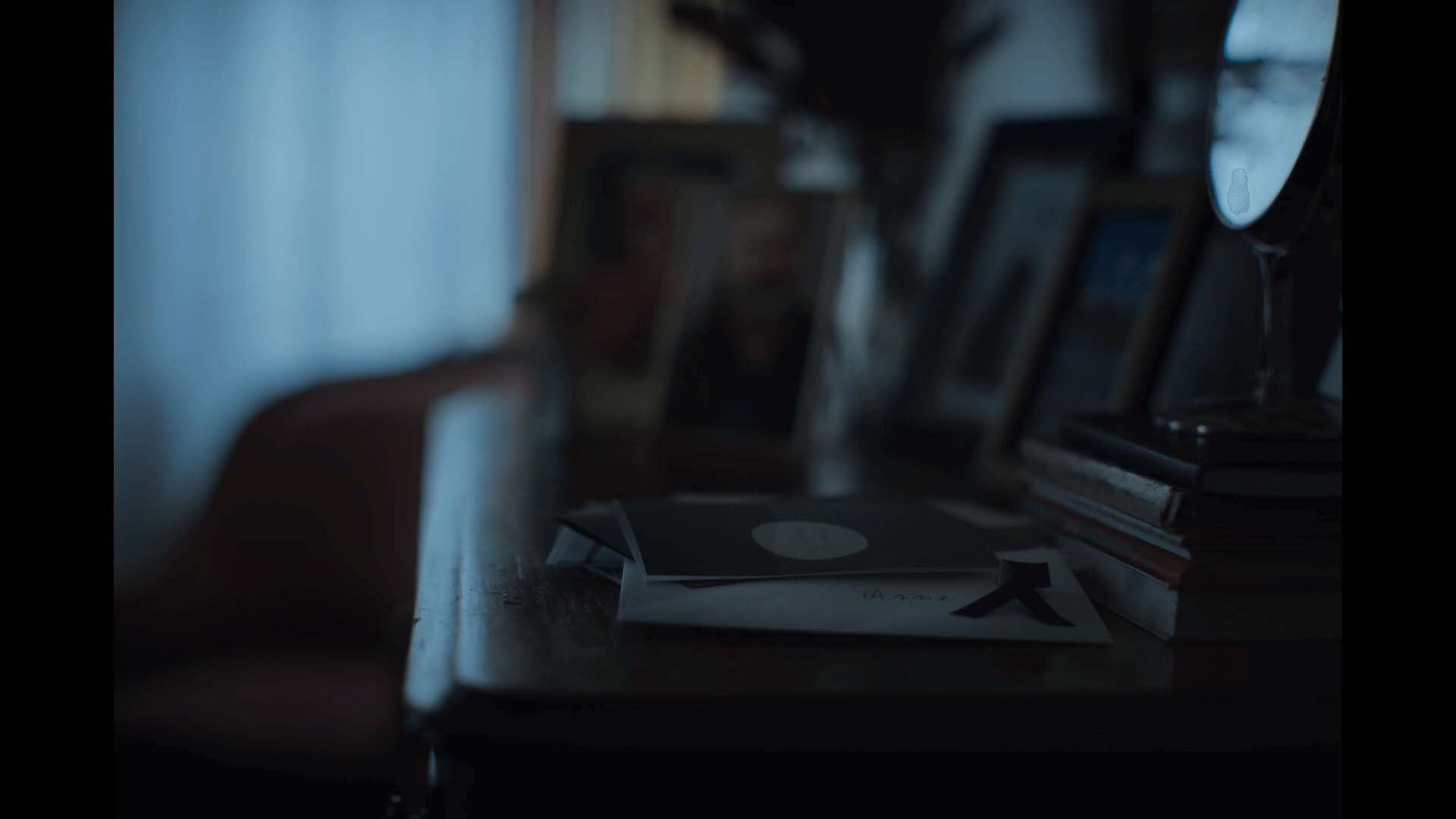 Still from the OBI Christmas commercial – a handwritten envelope on a sideboard with framed photos in a dimly lit room 